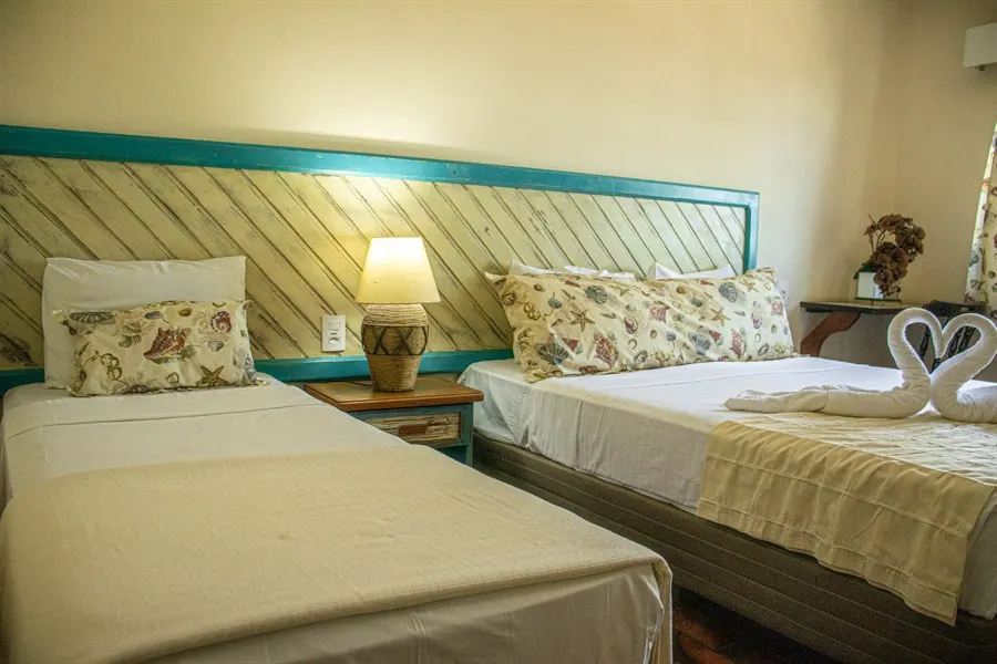 Quarto arrumado, com as camas feitas e toalhas dobradas